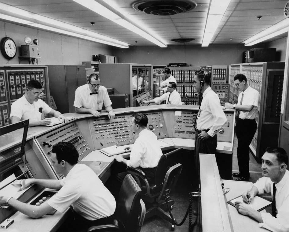 Project Mercury Guidance Computer, 1959-1963 Group of men sitting and standing at computer consoles and banks
