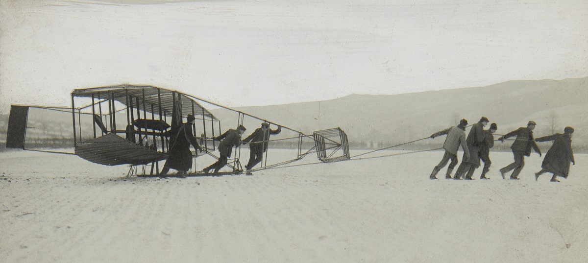 Ernest L. Jones Early Aviation Scrapbook, vol. 1 of 7 (A-B) / page 31 Black-and-white photo of a group of people pulling an early glider across snow or ice