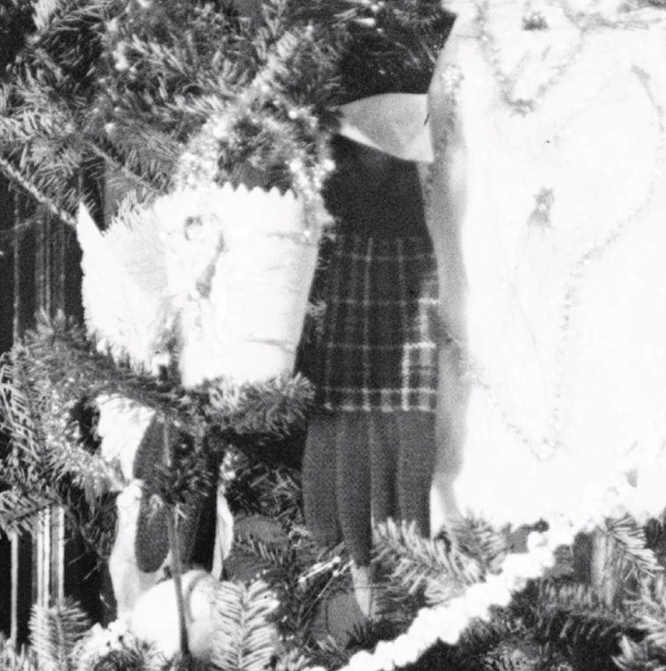 Scotch gloves hanging on the Wright Home Christmas tree, both in the original photo and during Holiday Nights in Greenfield Village GIF cycling through two images, one black-and-white and one in color, showing part of a Christmas tree with plaid gloves hanging on it