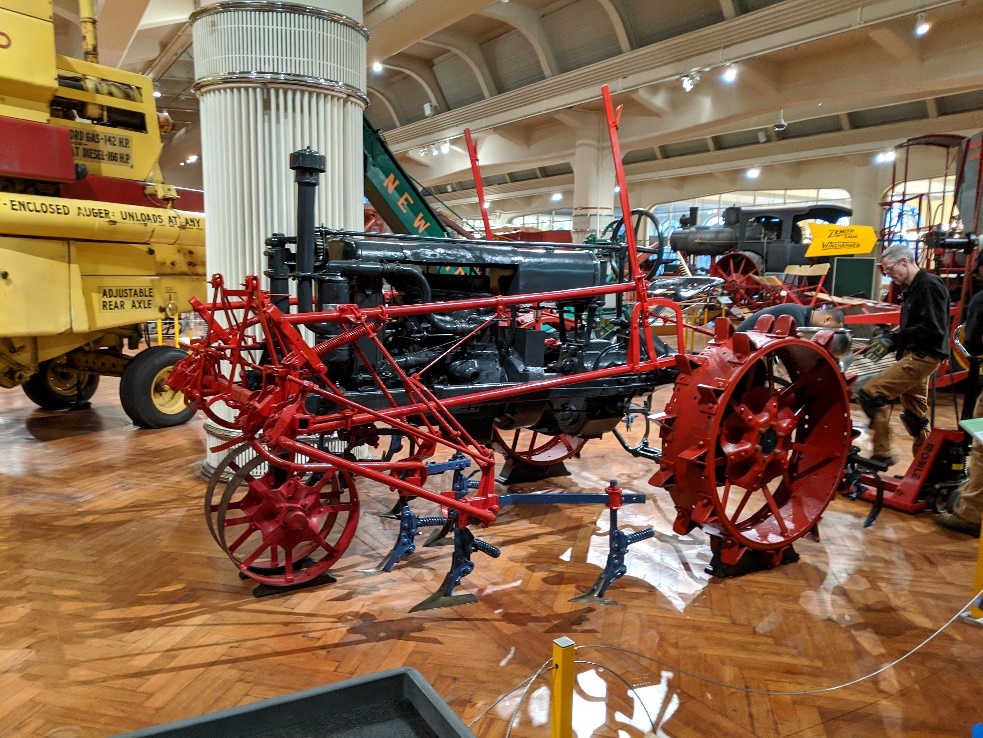 Farmall tractor after 2019 conservation project Tractor on wood floor in exhibit, surrounded by other equipment