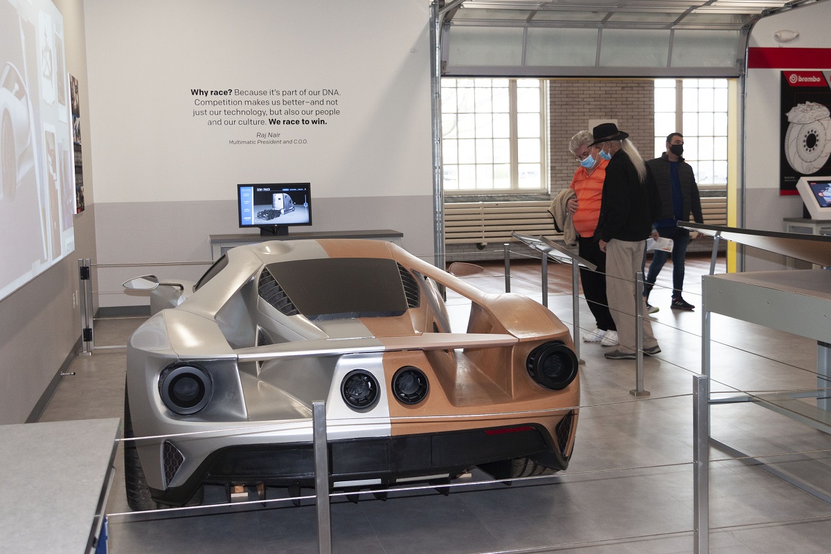 Guests check out the new Driven to Win exhibit on opening weekend Two people look at a low race car in a museum exhibit space that looks like a garage
