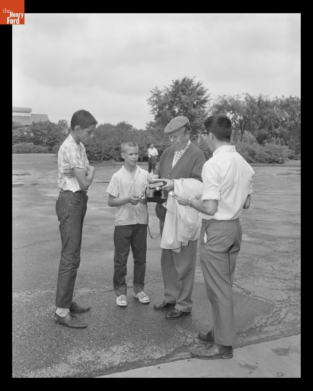 Older man in hat and sweater with three boys