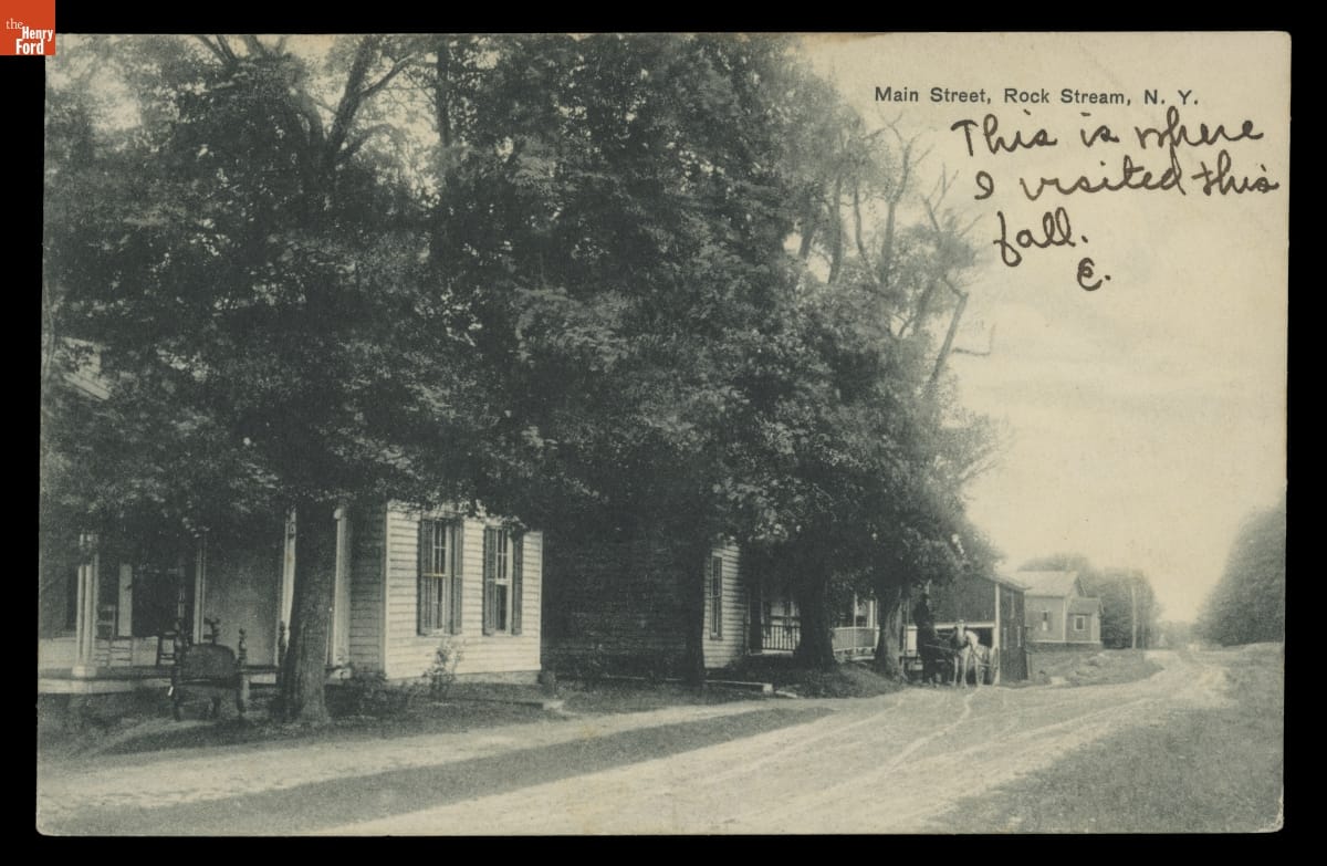 Main Street, Rock Stream, New York, 1908-1910 Black-and-white image of houses and trees along dirt road; printed and handwritten text