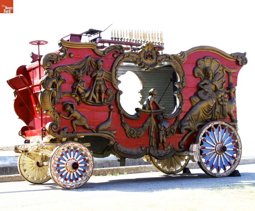 Large red wagon with colorful wheels, elaborately carved gold figures, and an open cut-out on either side