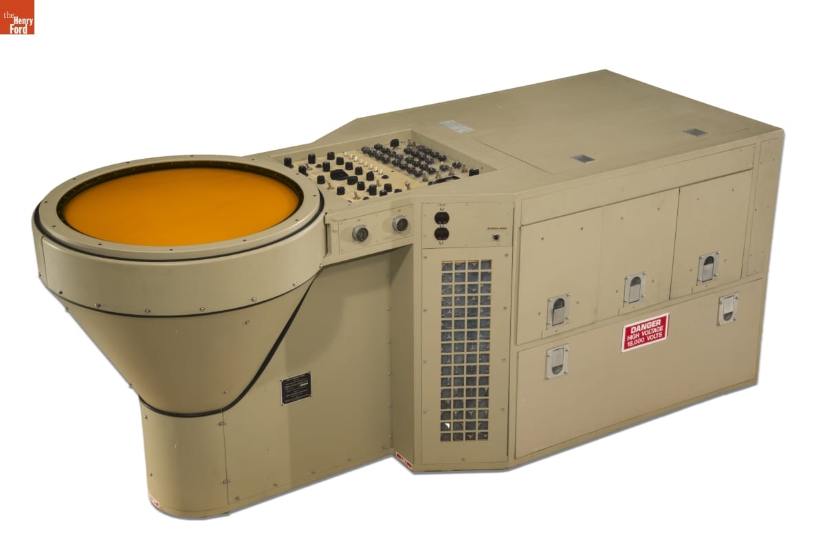 Large piece of beige metal equipment with round yellow screen (?) at one end and buttons and switches