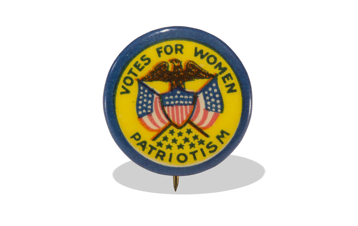 Button with image of eagle over crossed red, white, & blue American flags and shield, yellow background and blue rim, with text “Votes for Women – Patriotism”