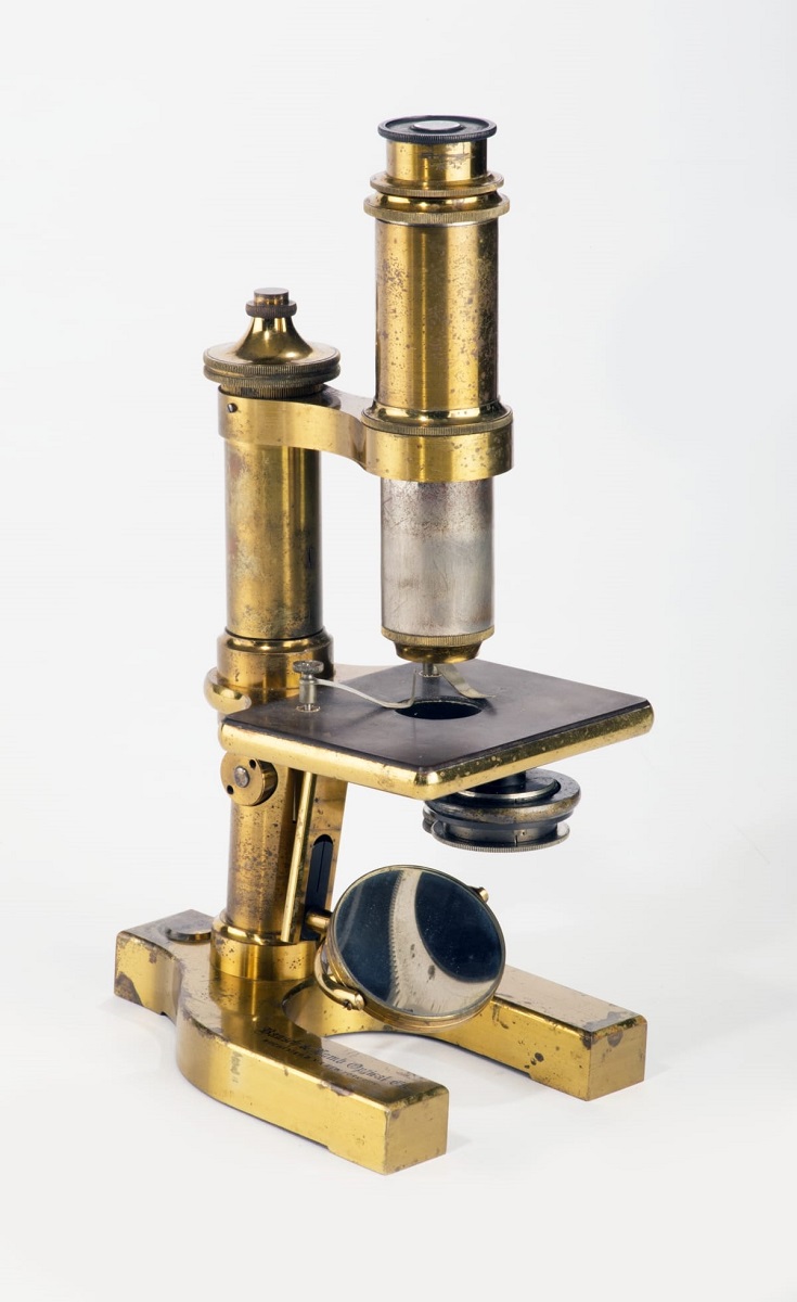 Brass microscope with long viewing tube, flat platform for specimens, and heavy brass feet