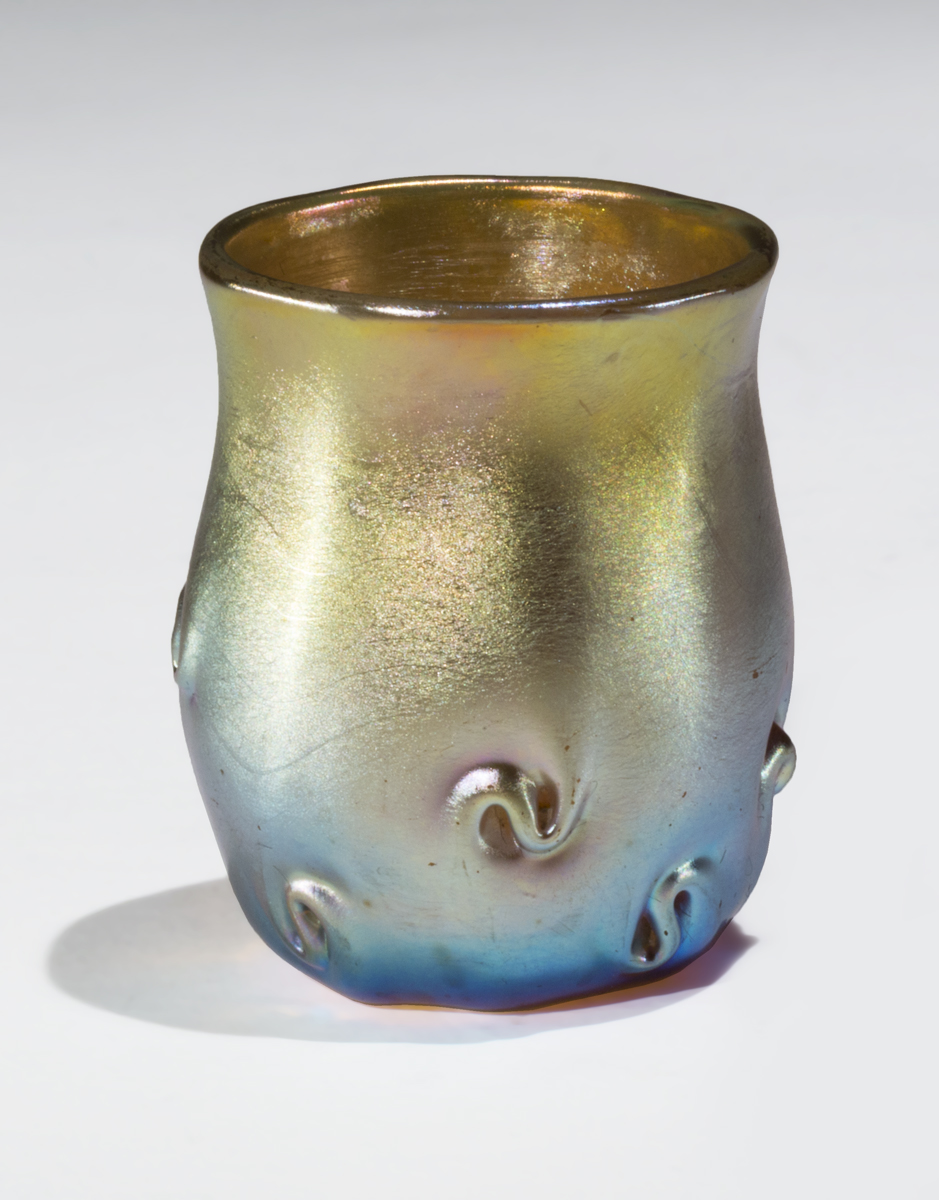 Iridescent blue and gold glass cup with dimensional s-shaped swirls on bottom