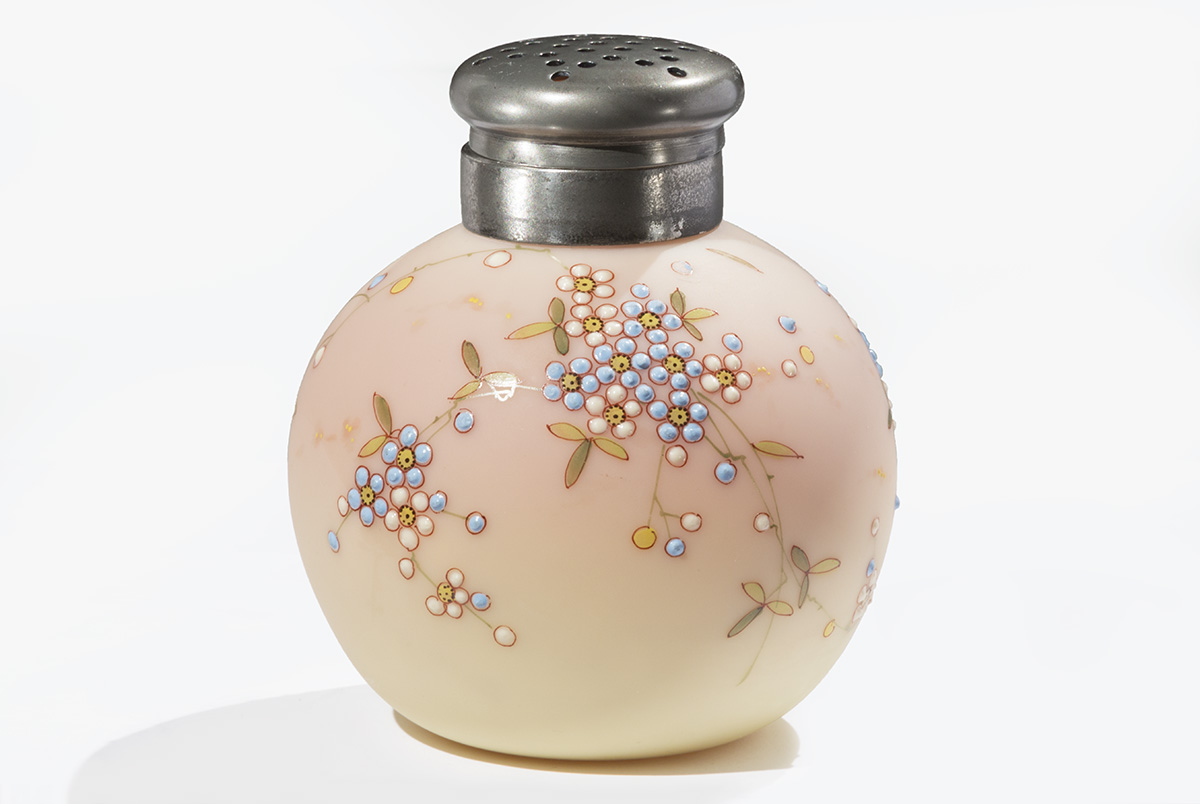 Small round, peach/cream-colored ceramic jar with pattern of stippled flowers, topped with a silver "shaker" lid