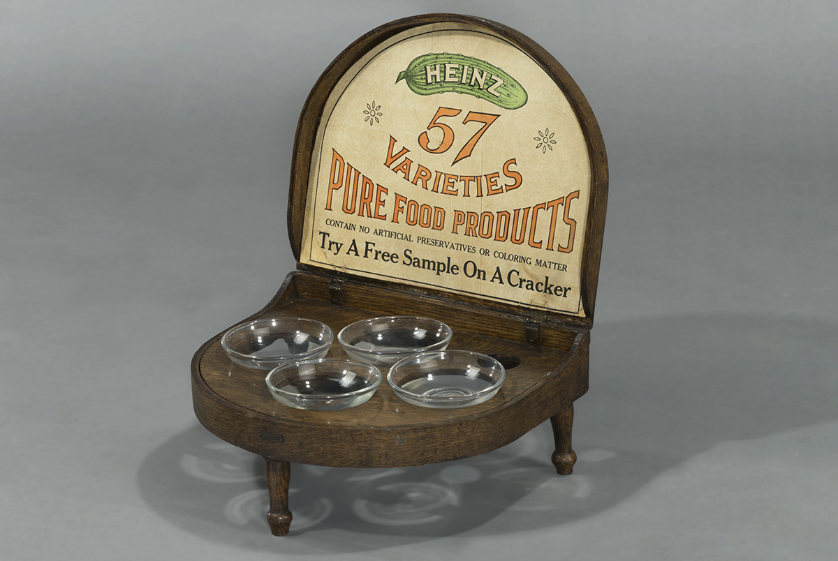 Wooden display holding four glass bowls and a sign with text
