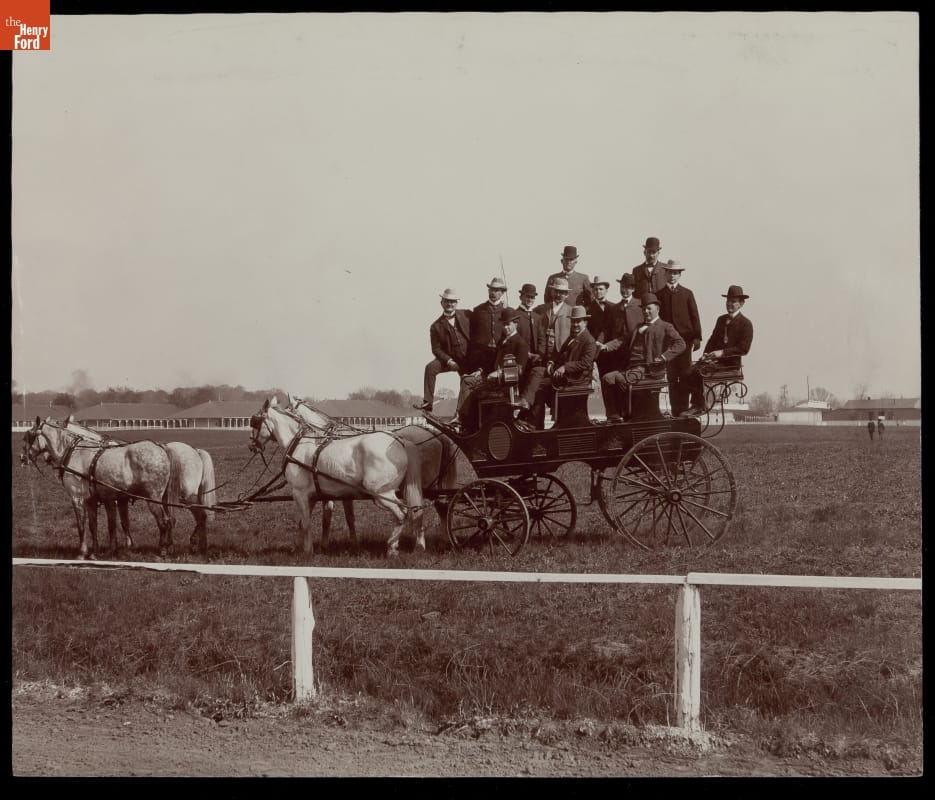 Governor Beckham and Party at the Races, Derby Day, Louisville, Kentucky, 1901 Four horses harnessed to a coach with quite a few passengers seated and standing in it, in a grassy area behind a white fence