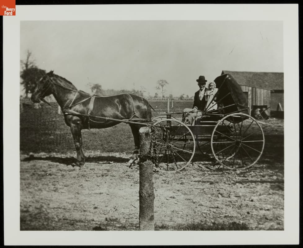 Man and infant in buggy hitched to horse