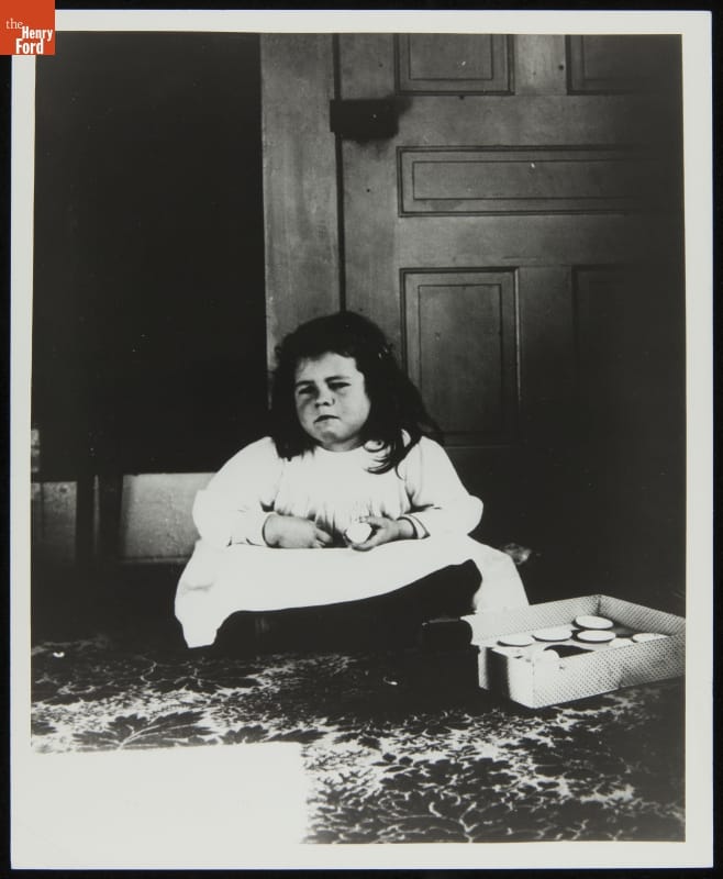 Bertha Wright, Age Five, Niece of the Wright Brothers, Daughter of Reuchlin Wright, circa 1900 Girl in white dress sitting cross-legged with somewhat grumpy expression on her face