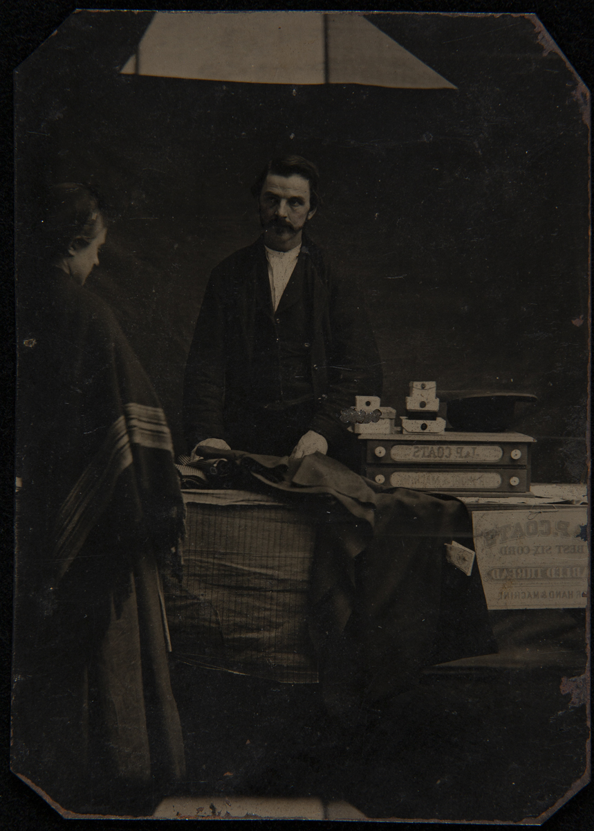 Salesman Displaying his Wares, circa 1860 Man behind table containing products while woman looks at them