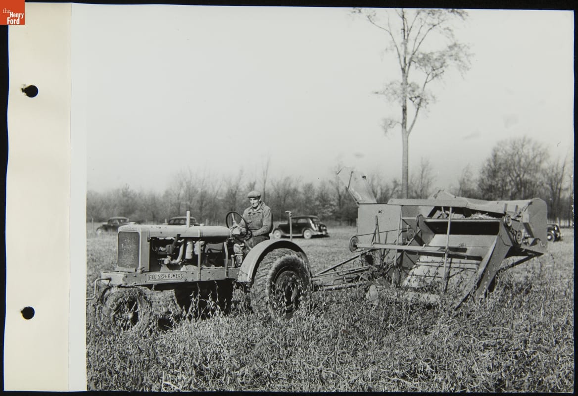 Man Driving an Allis-Chalmers Tractor, Threshing Soybeans at Michigan and Southfield Roads, Dearborn, Michigan, October 1936 Black-and-white photo of man driving a tractor with large equipment attachment behind it through a field