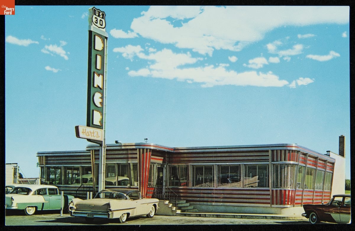 Low red-and-white striped diner with large sign and cars parked out front
