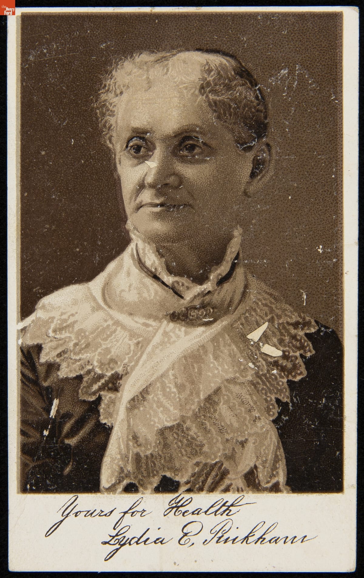 Torso and head of woman with elaborate lacy scarf pinned around her neck and chest; handwritten text