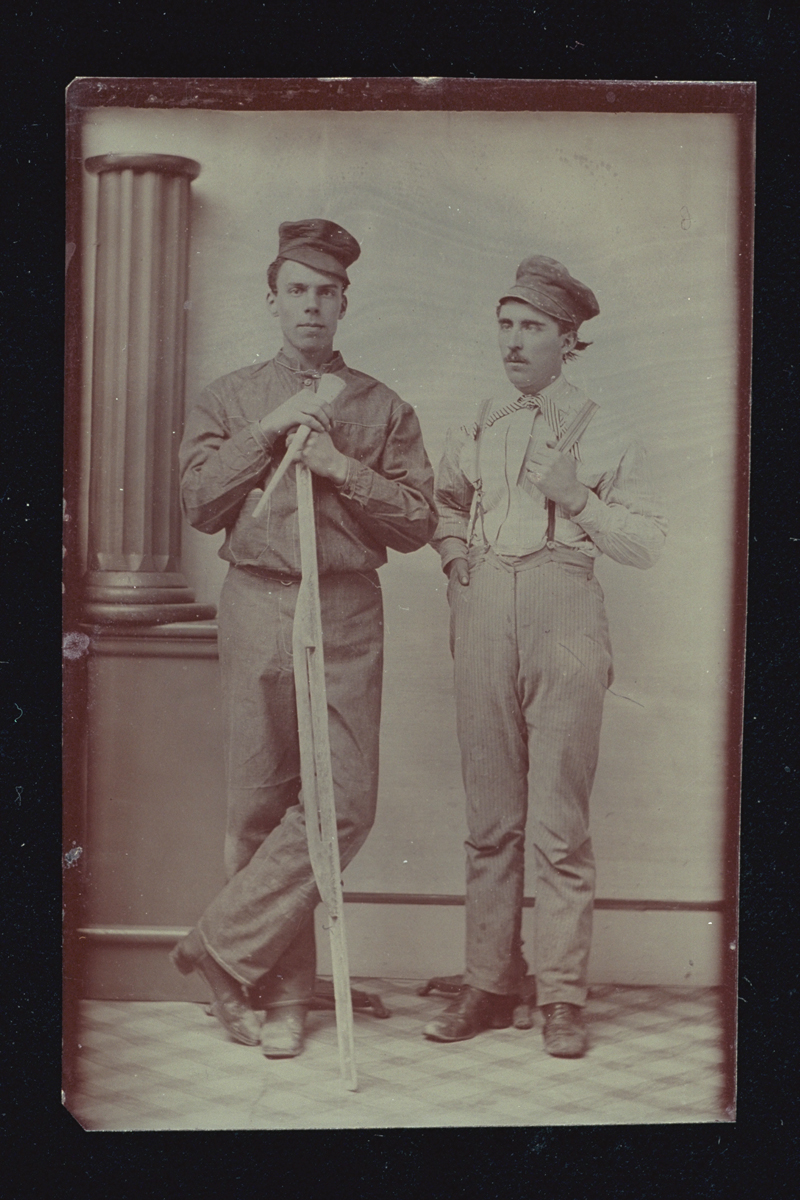 Plasterers with Their Tools, circa 1881 Two men in caps, one holding a long tool, standing next to a pillar
