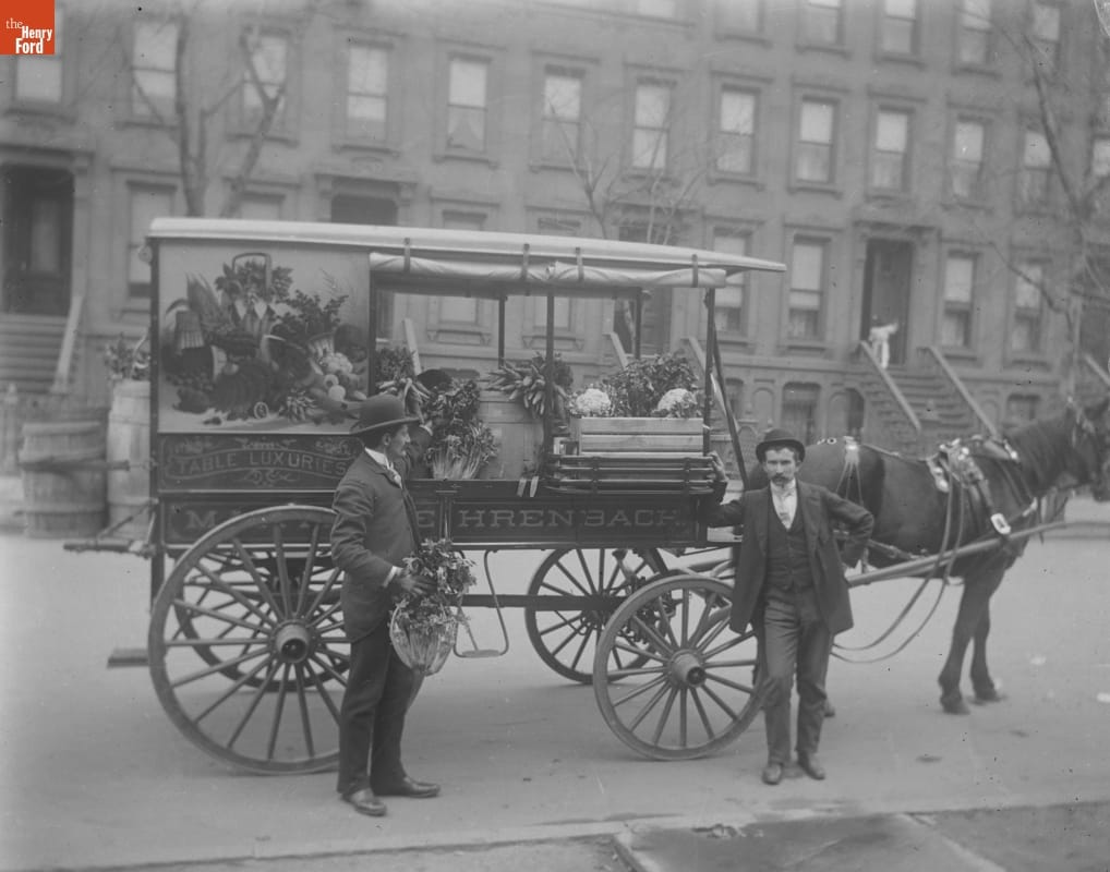 Delivery Wagon, Fehrenbach Table Luxuries, 1890-1915 Two men stand by a horse-drawn wagon, decorated with a painting of fruits and vegetables and containing produce