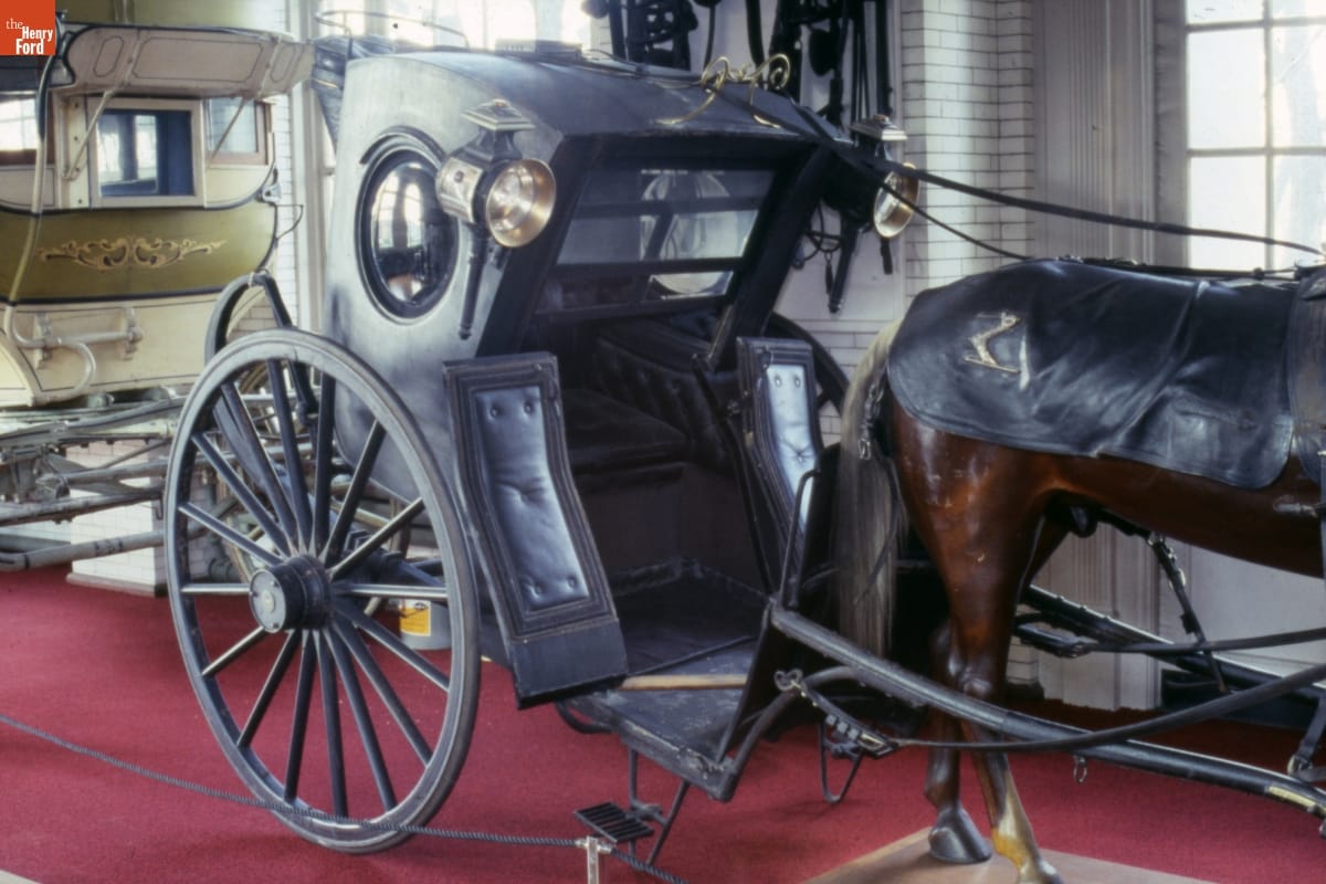 Joseph Thatcher Torrence's Hansom Cab, 1880-1890 Two-wheeled black carriage on display with other vehicles and horse mannequin
