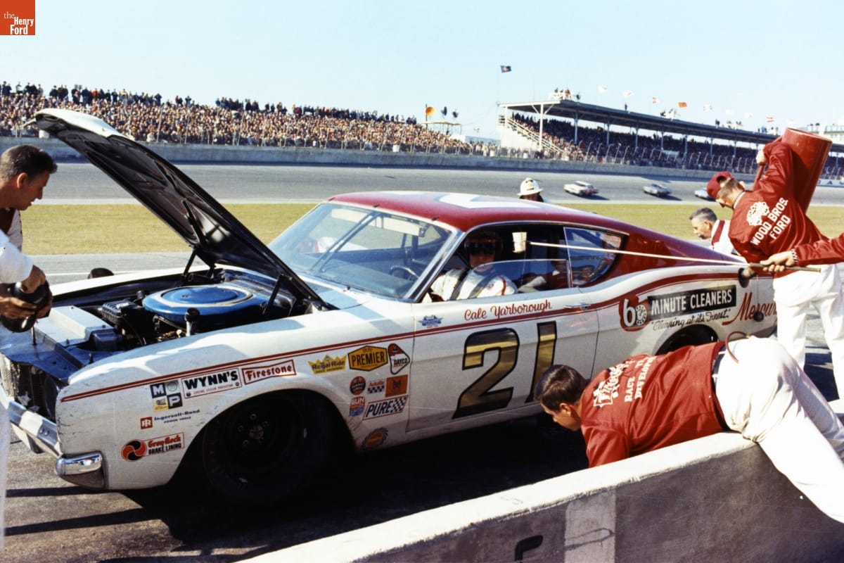 Cale Yarborough Seated in Ford Motor Company's Special Edition Mercury Cyclone Spoiler II, during the Daytona 500 Race, Florida, February 25, 1968 Man in helmet sits in white car with number "21" and logos on side at the side of a racetrack while several people work on the car