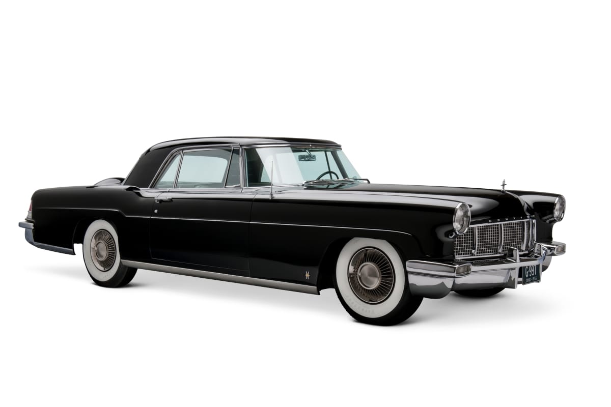 Black car with long hood and whitewall tires