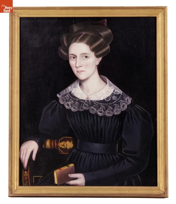 Portrait of woman with elaborate hairstyle wearing a dark dress with lace collar and holding a book