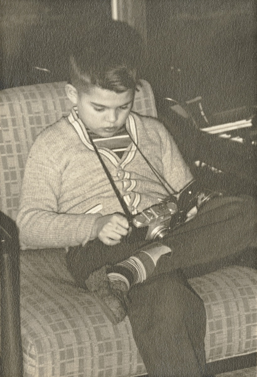 Frederick Birkhill as a child Black and white image of young boy sitting on chair looking at camera on a strap around his neck